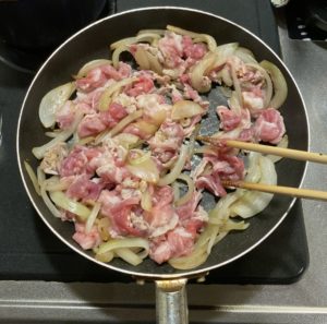 フライパンで炒めている豚肉と玉ねぎ